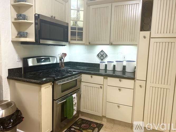 A kitchen with white cabinets and black countertops.