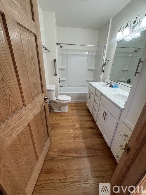 A bathroom with wooden floors and white fixtures.