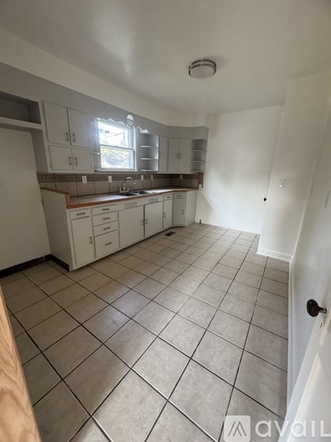 A kitchen with white cabinets and a tiled floor.