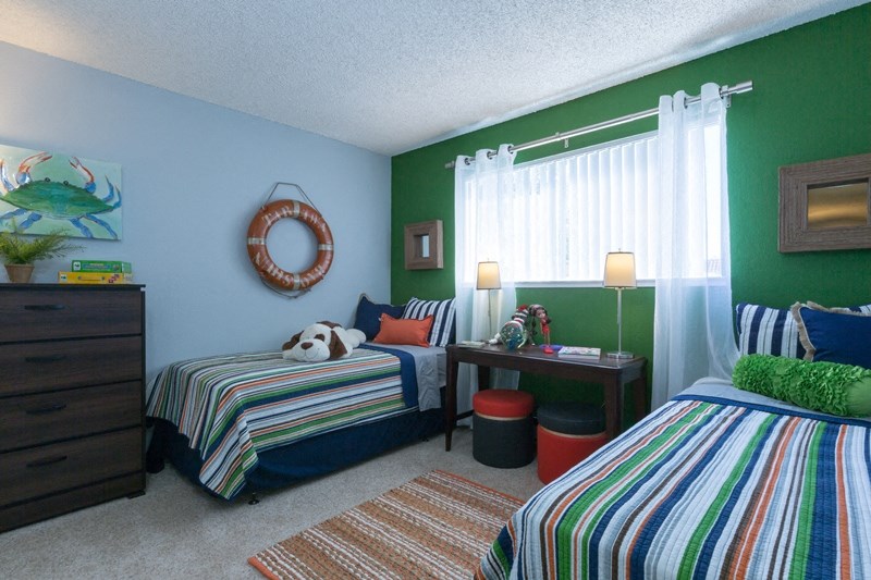 Bedroom with two beds with striped linen with a green wall behind them