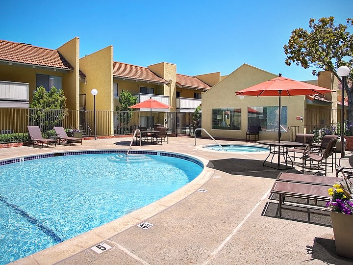 Sienna Apts Pool and Jacuzzi area with orange umbrellas covering sitting areas.