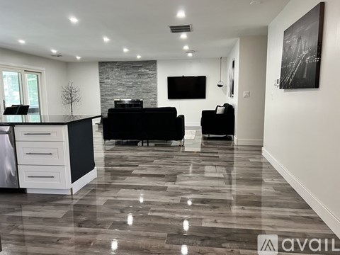 A modern living room with a black couch and a television mounted on the wall.