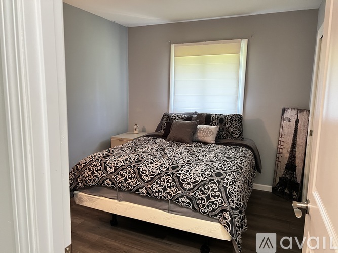 A bedroom with a bed and a window with blinds.
