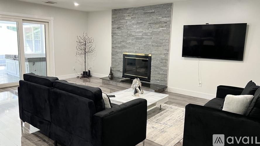 A living room with black couches and a stone fireplace.