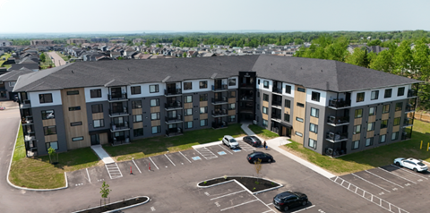 A large apartment complex with a parking lot in front.