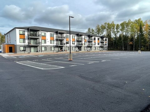 A parking lot in front of a modern apartment building.