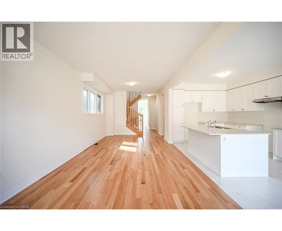 A spacious room with wooden flooring and white walls.