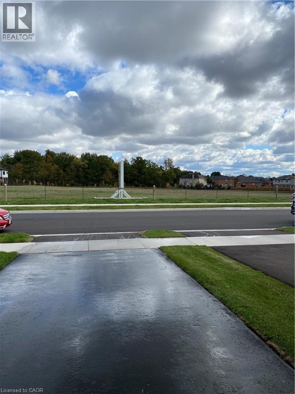 A wet road in front of a grassy area with a monument in the distance.