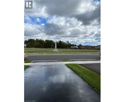A wet road in front of a grassy area with a monument in the distance.