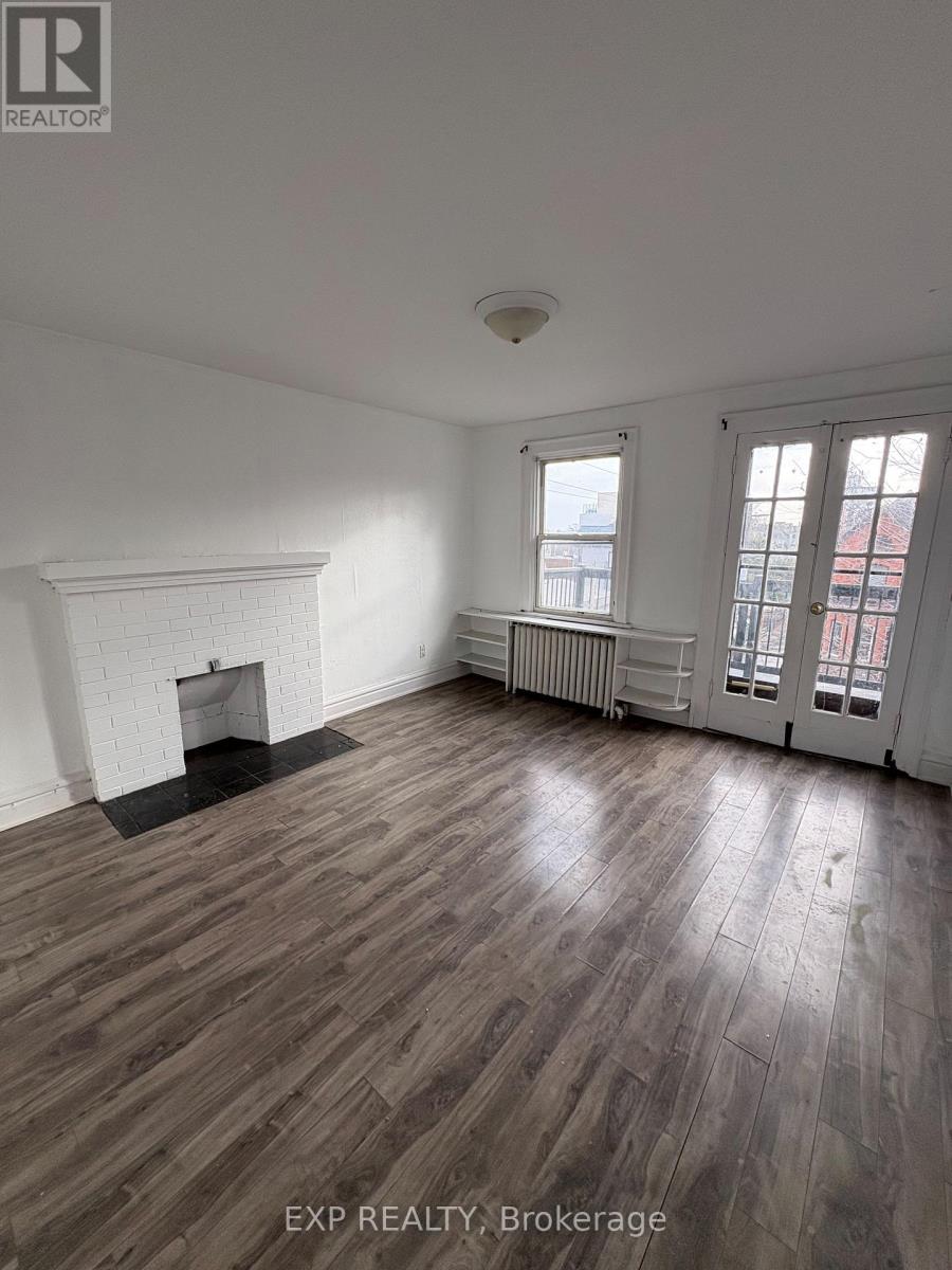 A room with wooden flooring and a fireplace.