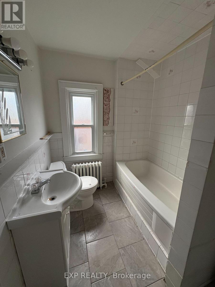 A white bathroom with a window and a radiator.