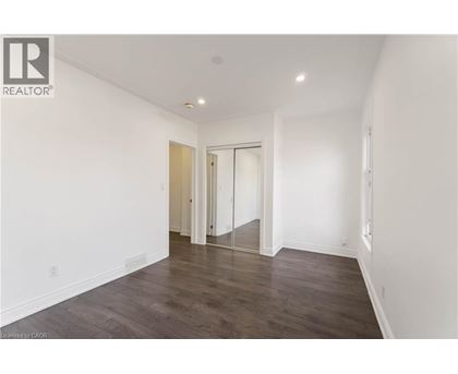 A spacious room with wooden flooring and white walls.