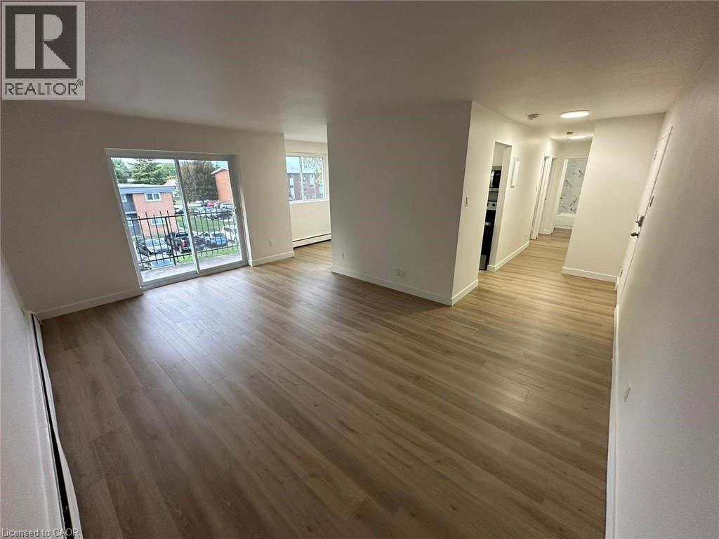 A spacious room with wooden flooring and white walls.
