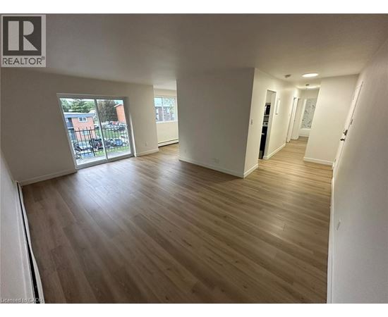 A spacious room with wooden flooring and white walls.