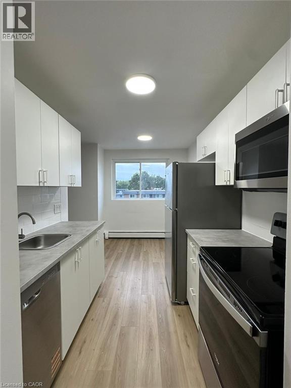 A modern kitchen with white cabinets and black appliances.