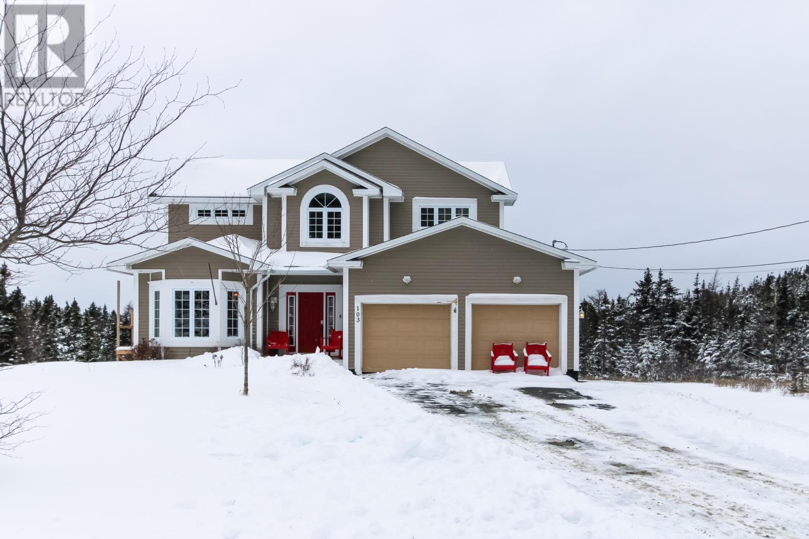 A house with a red door and garage door is surrounded by snow.