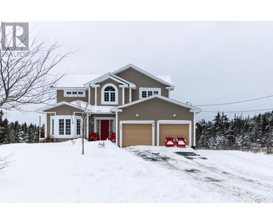 A house with a red door and garage door is surrounded by snow.