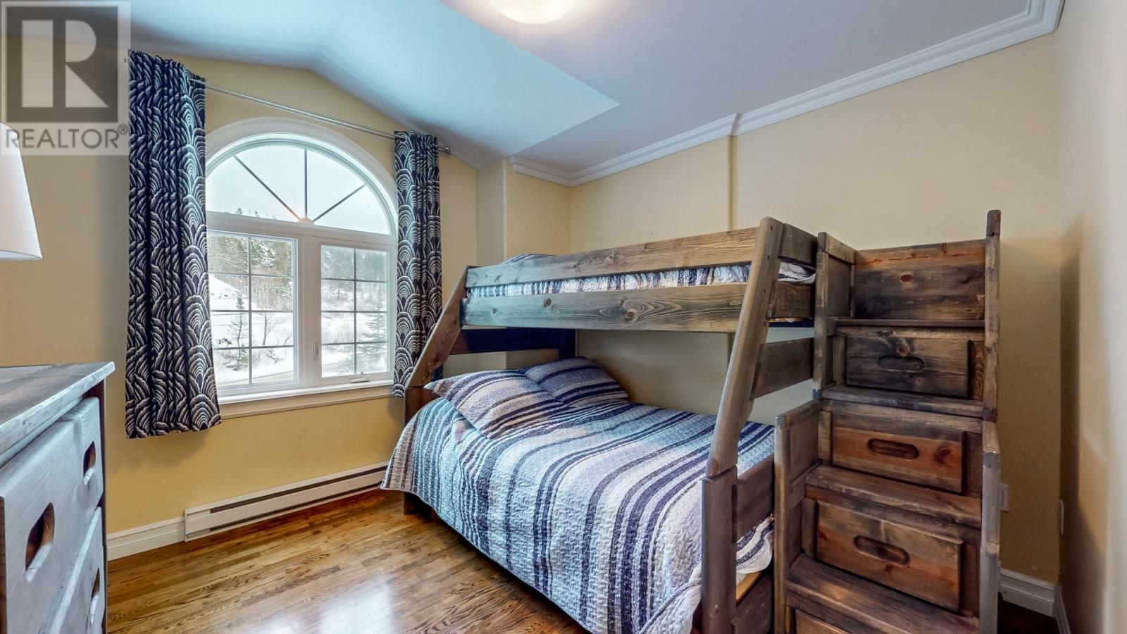A bedroom with a bunk bed and a window with curtains.