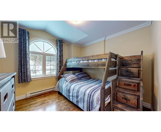 A bedroom with a bunk bed and a window with curtains.