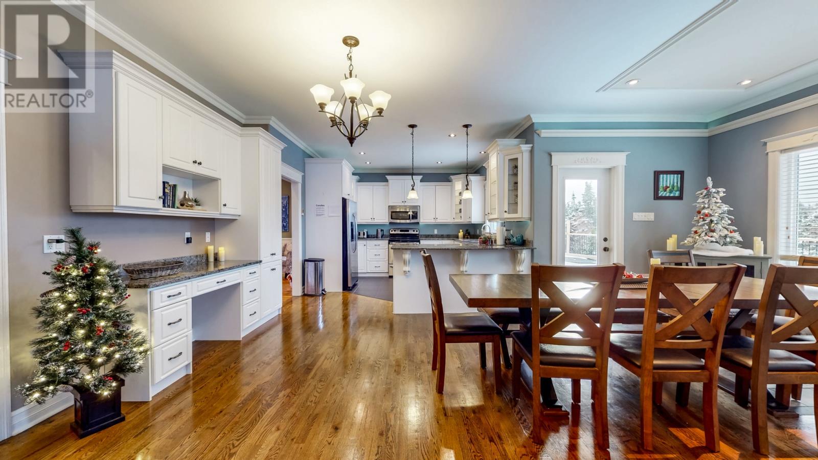 A Christmas tree is placed in a kitchen with a dining table and chairs.