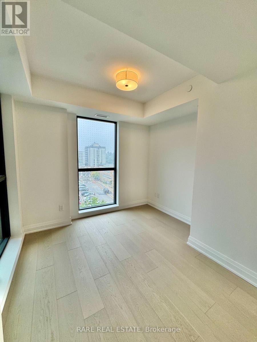 A spacious room with a large window and wooden flooring.