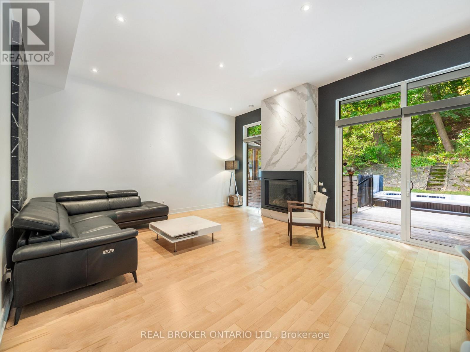 A living room with a black leather sofa and a fireplace.