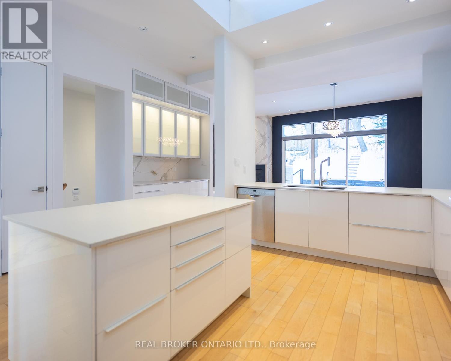A modern kitchen with white chairs and a marble backsplash.