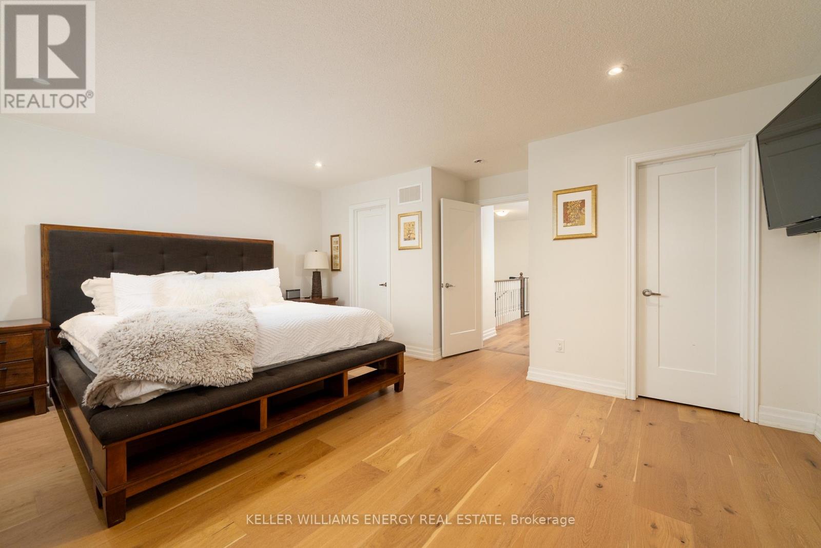 A bedroom with a large bed and wooden floors.