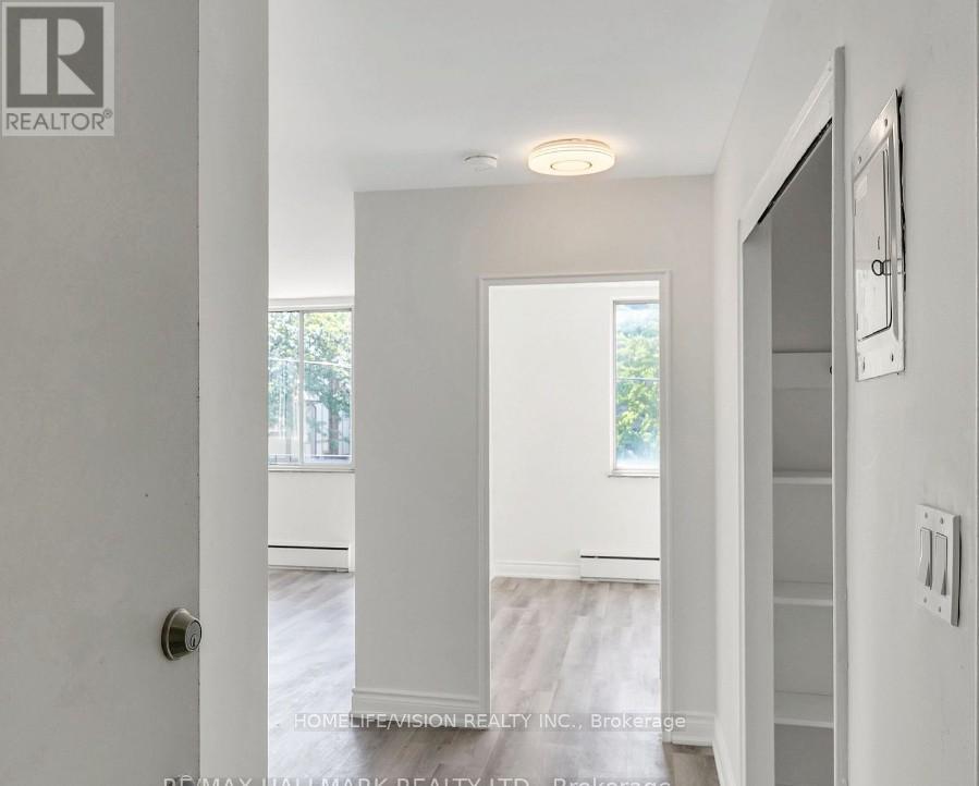 A white hallway with a door on the left and a window on the right.