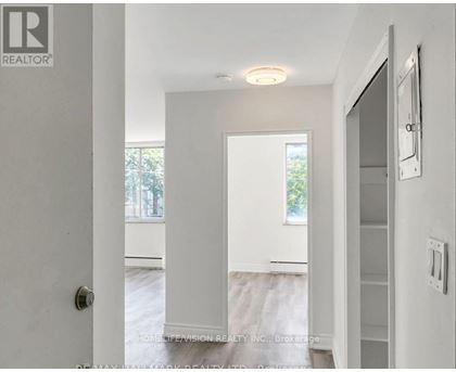 A white hallway with a door on the left and a window on the right.