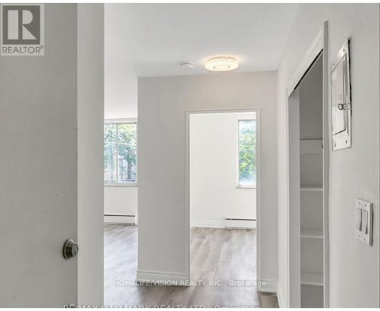 A white hallway with a door on the left and a window on the right.