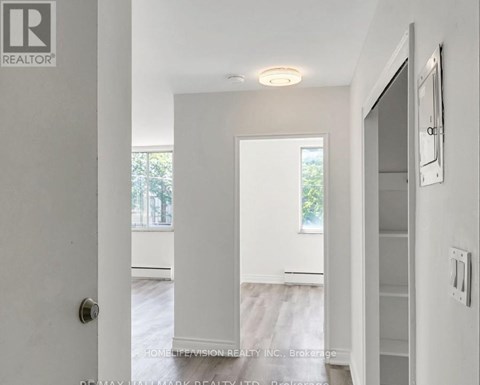 A white hallway with a door on the left and a window on the right.