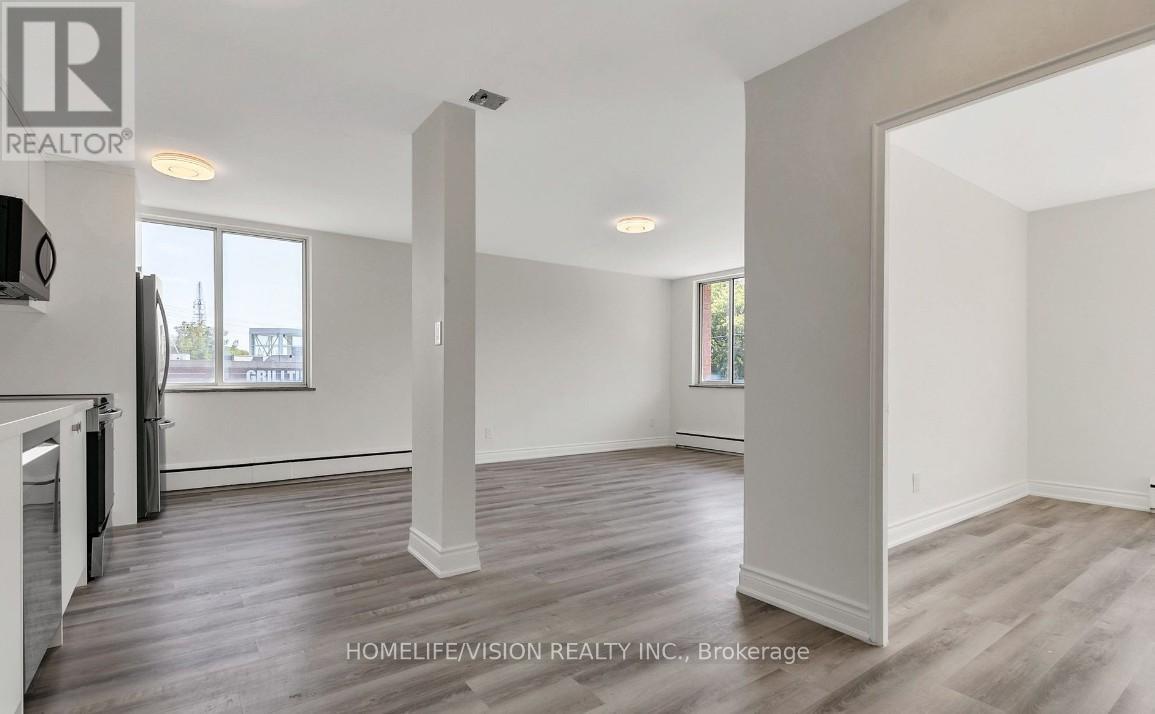 A spacious room with wooden flooring and white walls, part of a real estate listing.