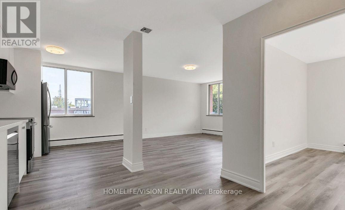 A realtor photo of a large empty room with wood floors and white walls.