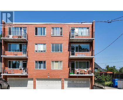 A red brick building with balconies and a sign that reads "HOMELIFE VISION REALTY INC., Brokerage".