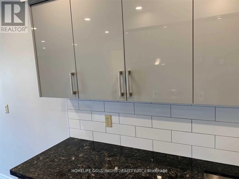 A kitchen counter with a tile backsplash and cabinets above it.