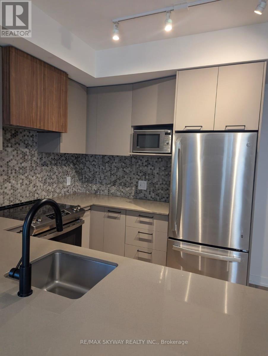 A modern kitchen with a stainless steel refrigerator and a black faucet.