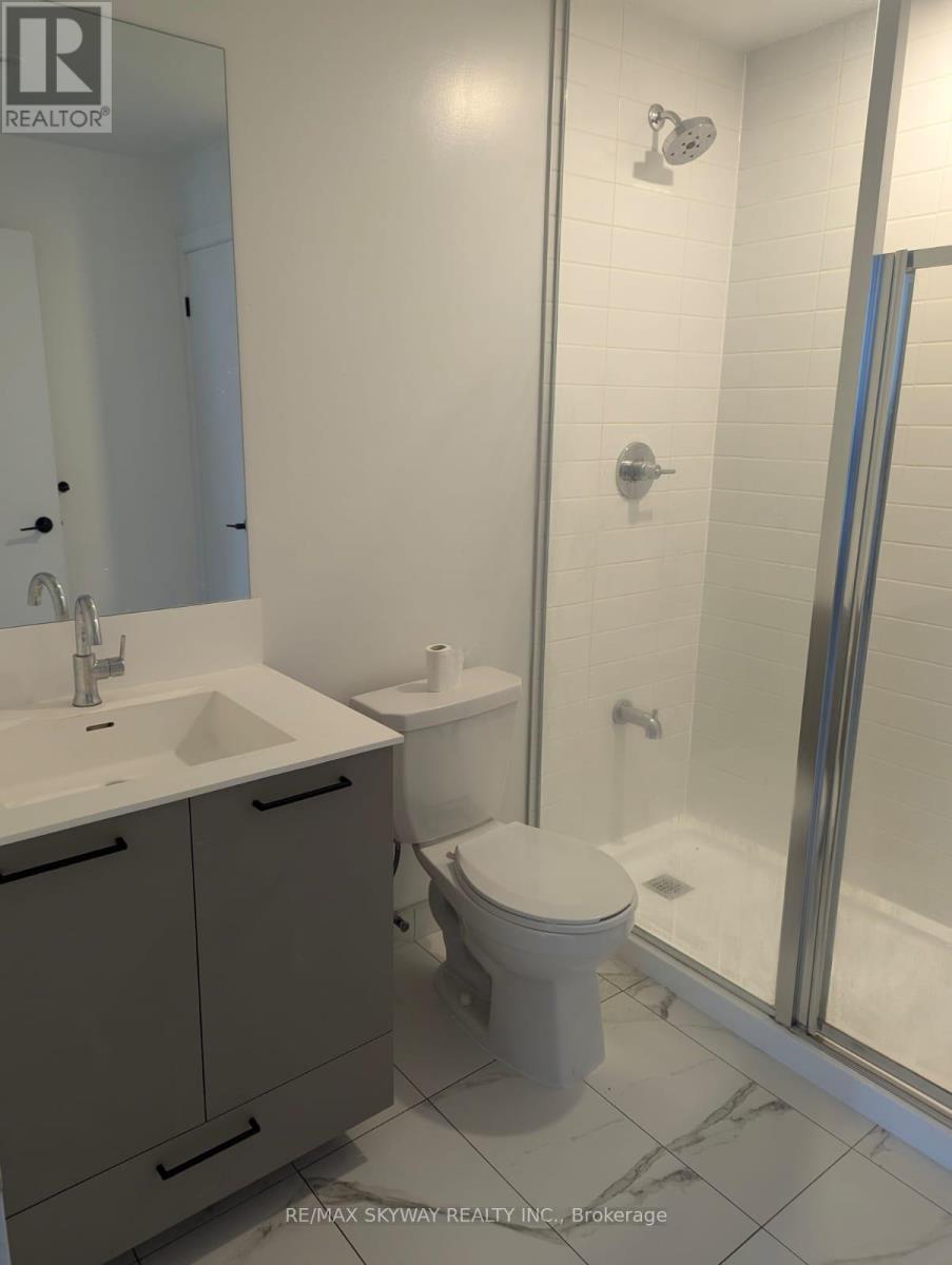 A white toilet sits in a bathroom next to a sink.