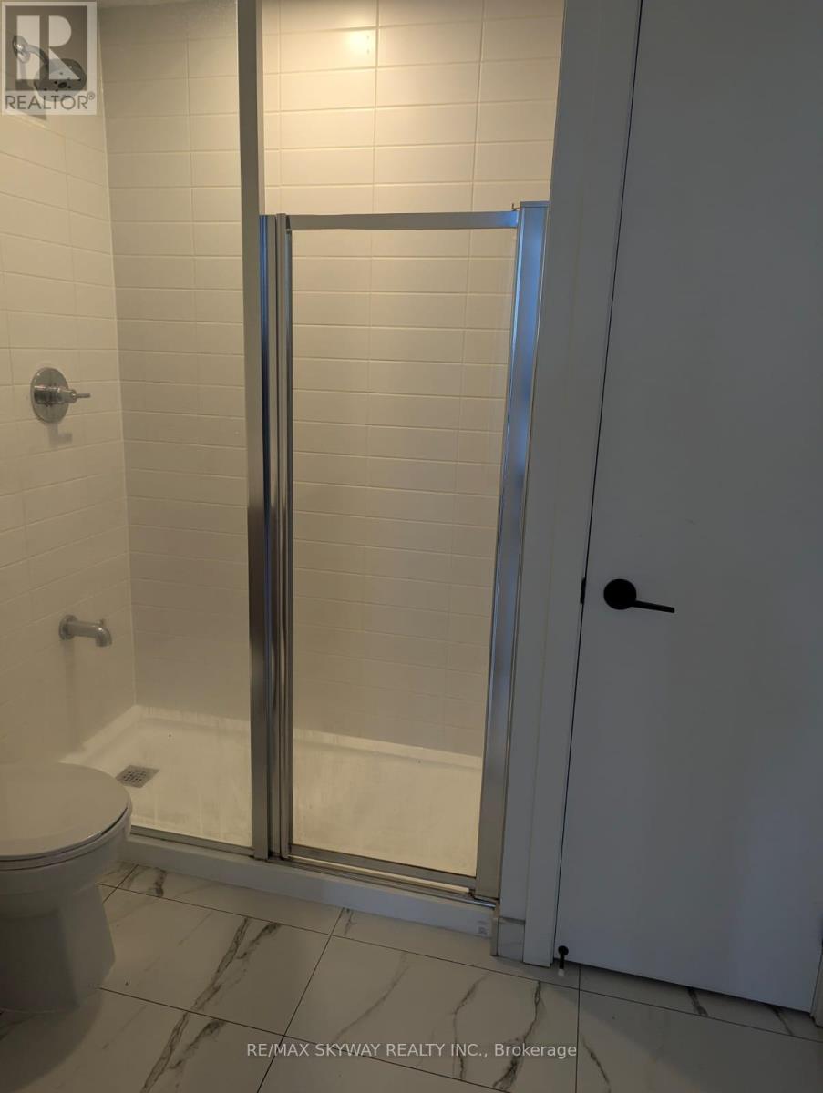 A white toilet is in a bathroom with a glass shower door.