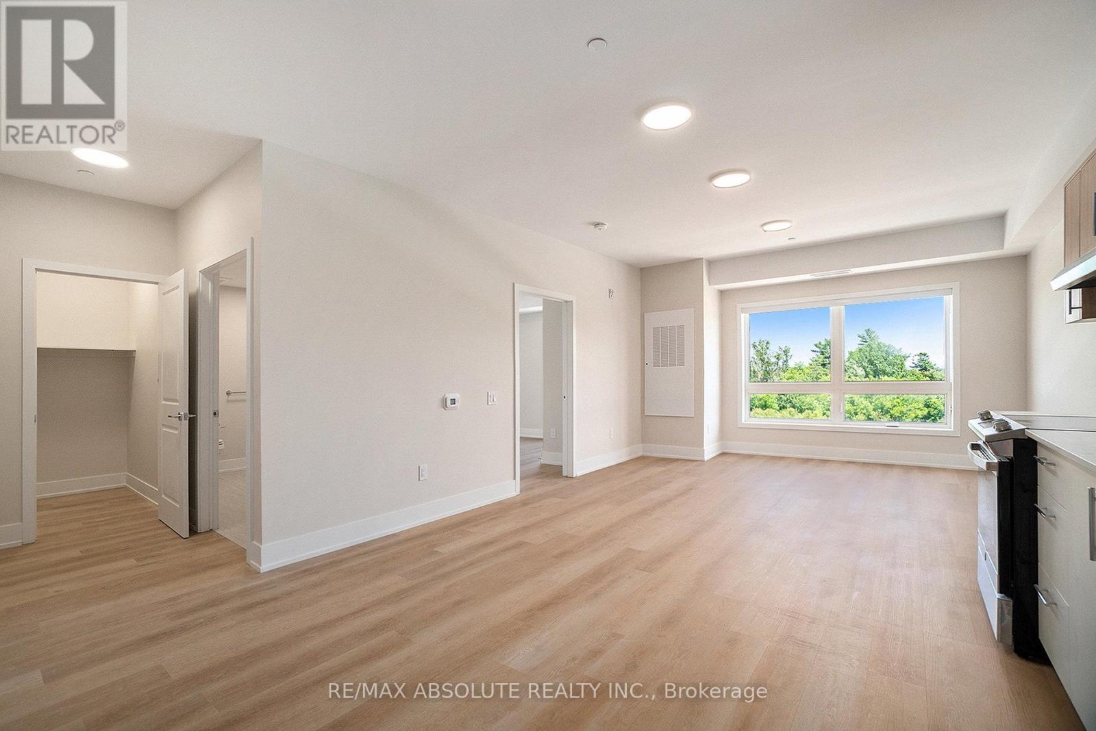 A spacious room with wooden floors and a large window overlooking a green landscape.