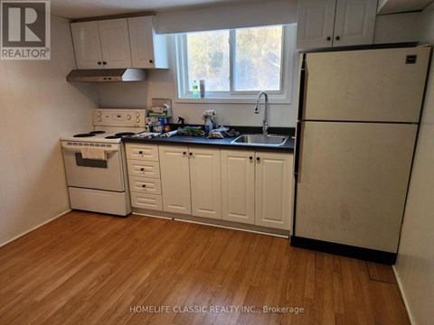 A kitchen with white cabinets and a black fridge.