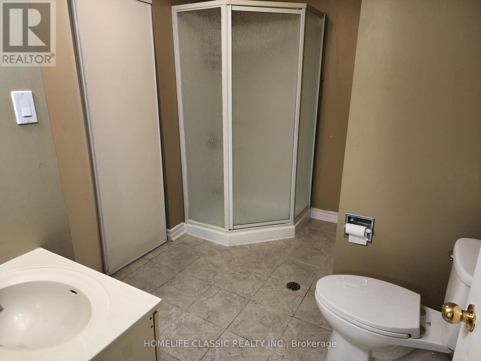 A bathroom with a toilet, sink, and shower stall.