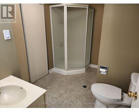 A bathroom with a toilet, sink, and shower stall.