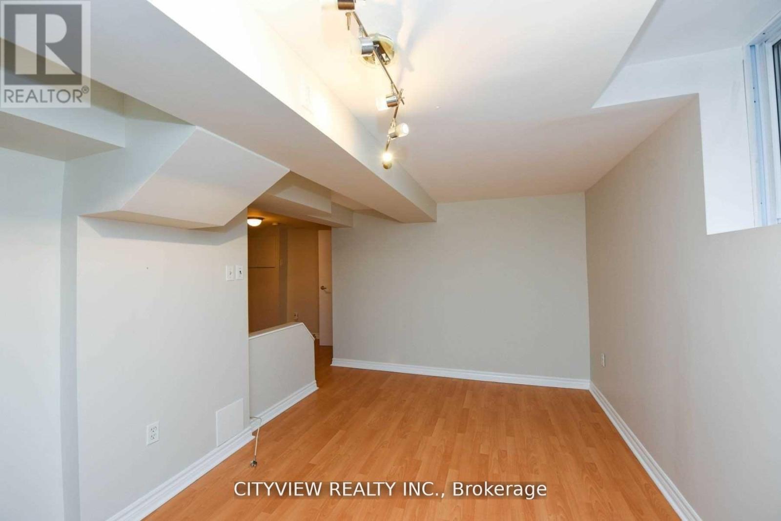 A room with a wooden floor and white walls, with a door in the middle of the room.