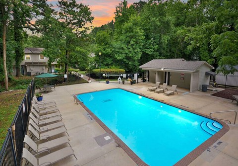 A swimming pool surrounded by lounge chairs and trees.