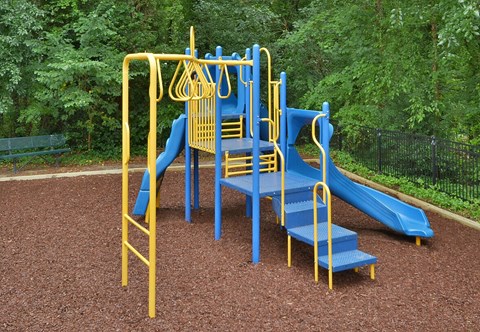 A playground with a blue slide and yellow handrails.