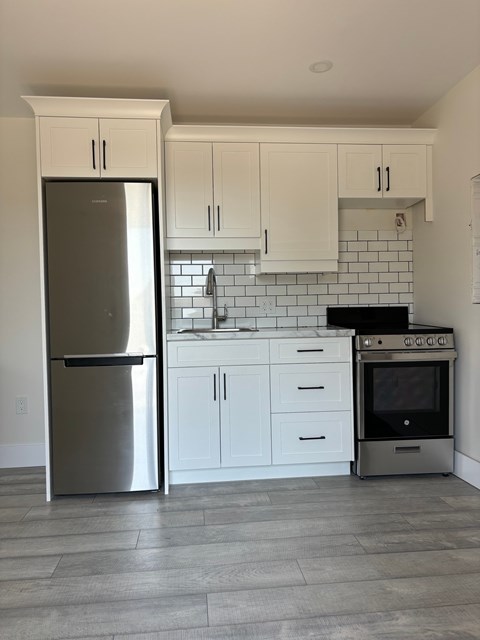 A kitchen with a stainless steel refrigerator, oven, and cabinets.