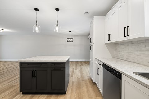 A kitchen with black and white cabinets and a wooden floor.