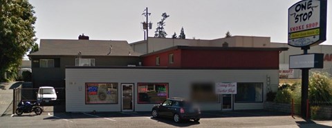 A One Stop Smoke Shop with a car parked in front.