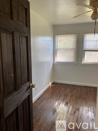 A room with a wooden floor and a white ceiling fan.
